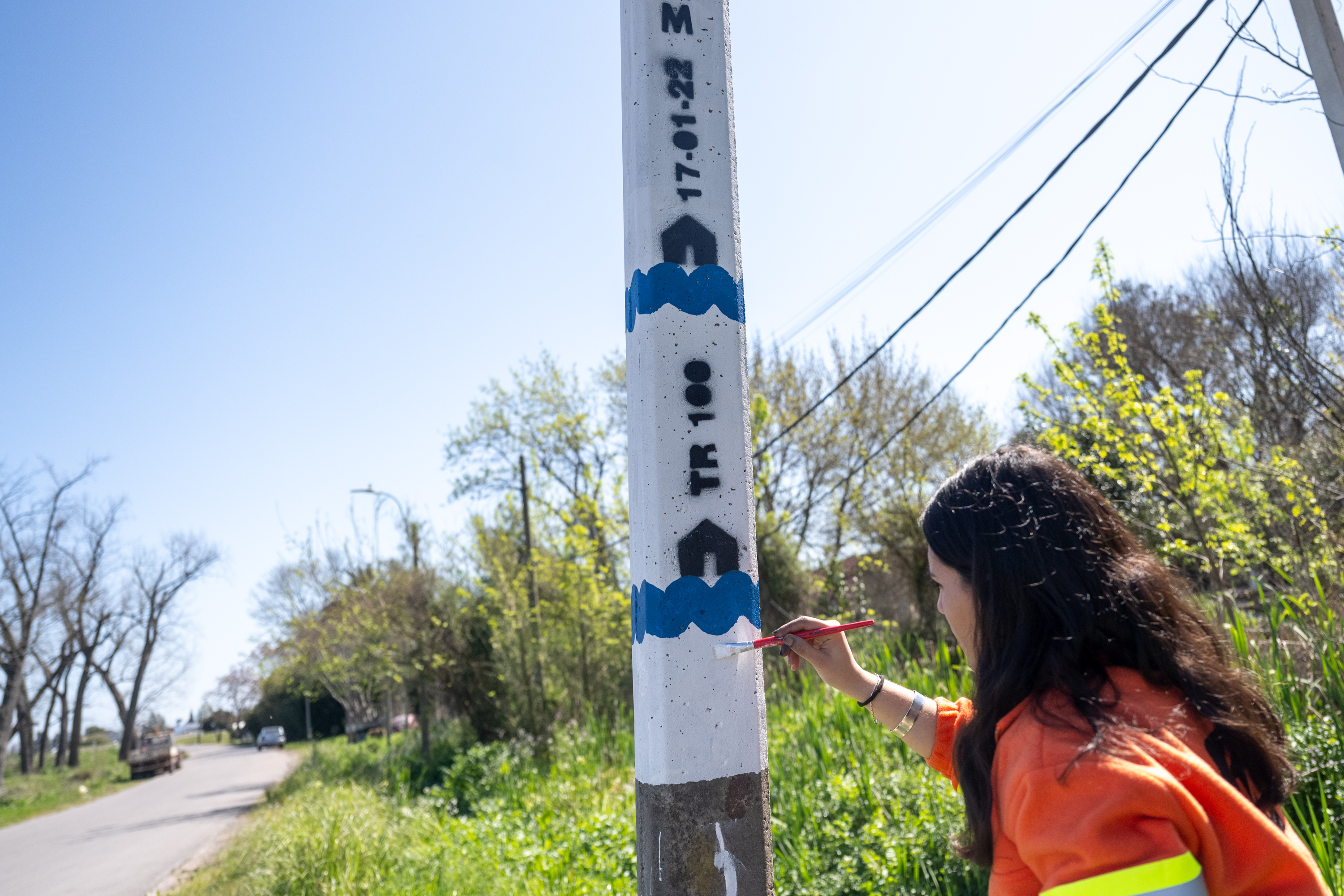 Mujer pintando columna de aviso temprano de inundaciones en el arroyo Manga