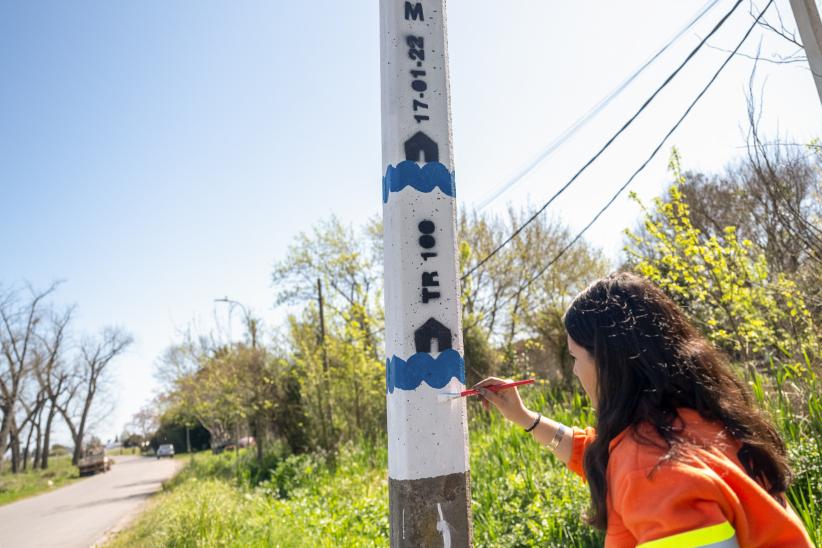 Mujer pintando columna de aviso temprano de inundaciones en el arroyo Manga