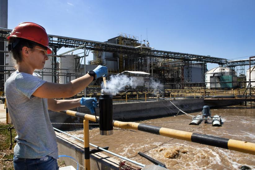 La investigadora Patricia Bovio Winkler y el encargado de la planta de tratamiento de efluentes de una industria uruguaya toman muestras de una pileta en un biorreactor. 