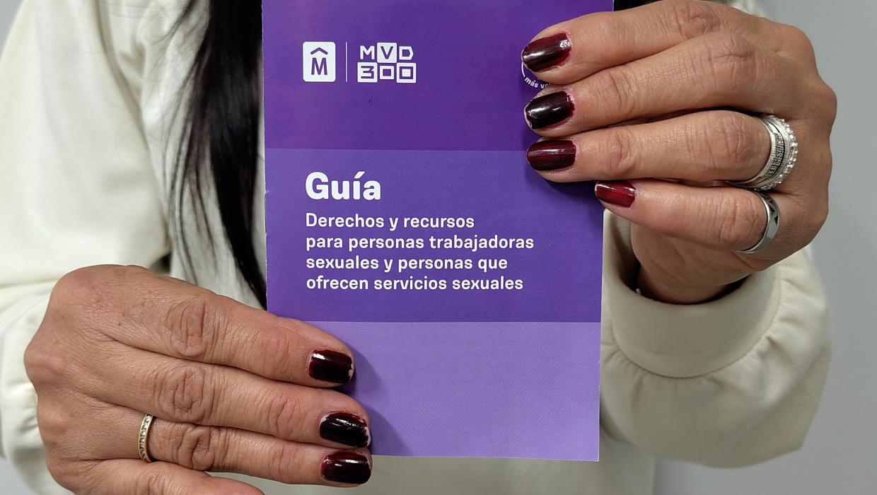 Una mujer muestra a cámara la guía de derechos para trabajadoras sexuales.