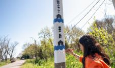 Mujer pintando columna de aviso temprano de inundaciones en el arroyo Manga