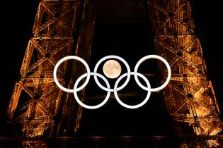 La luna es vista detrás de los aros olímpicos exhibidos en la 