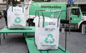 Dos bolsones para la recolección y en el fondo se ve un camión de recoleccion con el logo Montevideo más verde