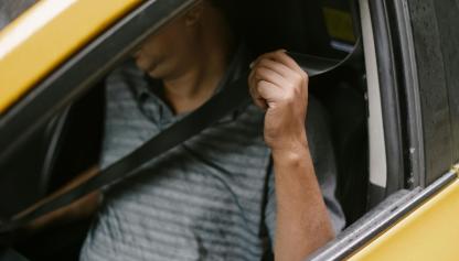 Hombre colocandose el cinturón de seguridad, el cual se destaca en la imágen.