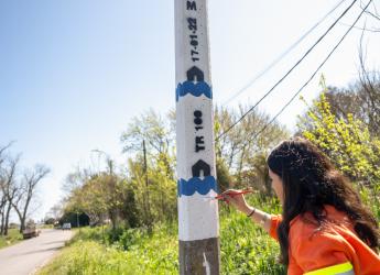Mujer pintando columna de aviso temprano de inundaciones en el arroyo Manga